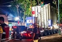 TRAFO RAKSASA LEWAT - Polisi dan pertugas mengawal iringan truk pengangkut trafo raksasa berukuran lebih dari 200 ton lewat jalur jalan nasional Banyuwangi-Kalipuro (Foto : Jatim.co) 